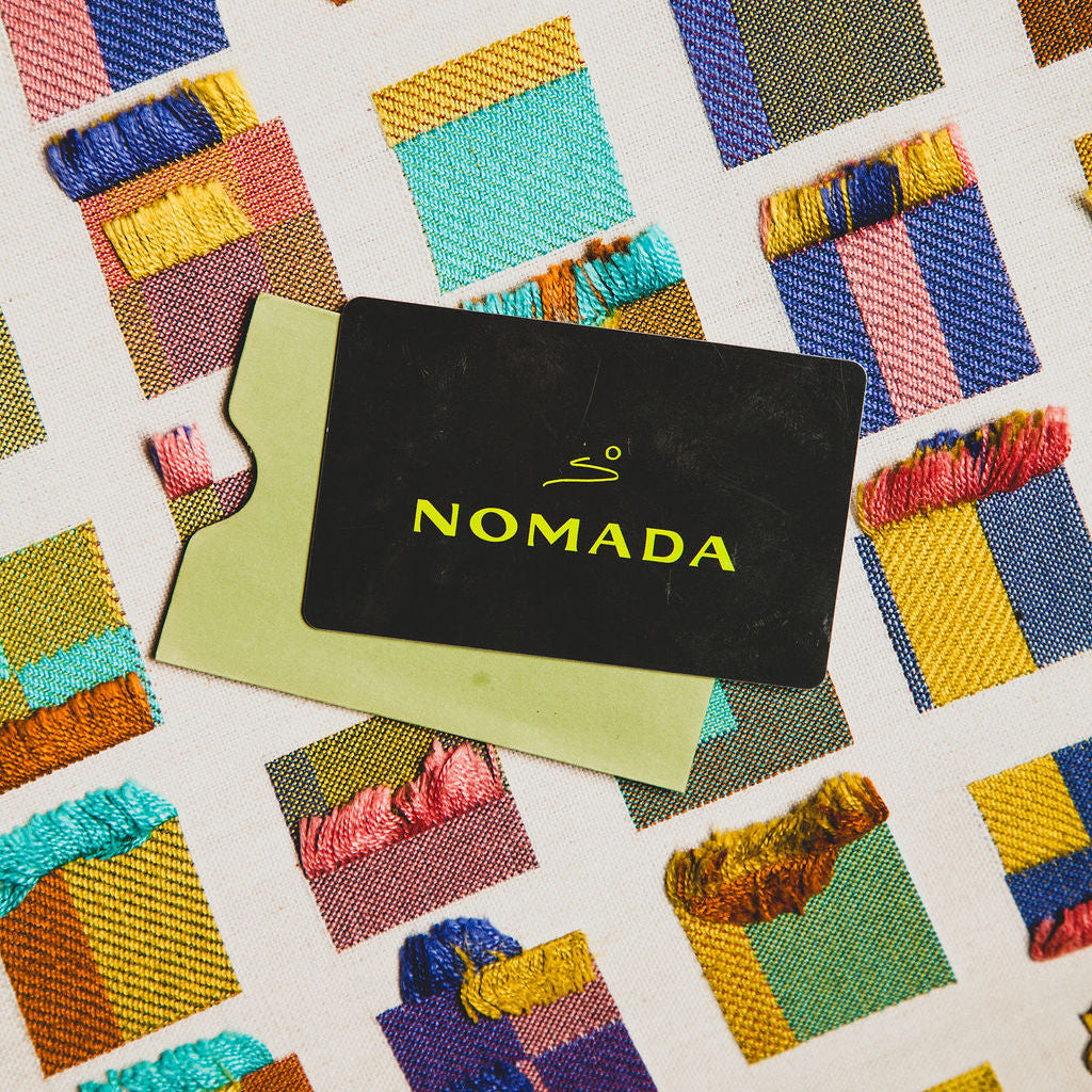 Nomada card on a fabric background with colorful patterns